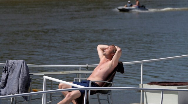 A man enjoys the sun on his boat on the river Thames near Hammersmith in London, July 15, 2022. British weather forcaster the Met Office has said temperatures are like to peak at the beginning of next week and has extended its Amber weather warning from Sunday to Tuesday. (AP)