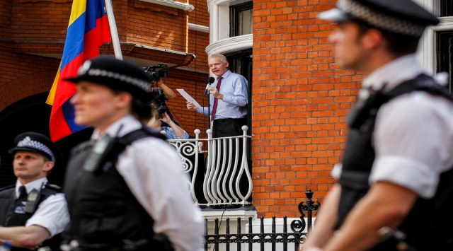 British police stand guard as WikiLeaks founder Julian Assange, center, address media and supporters from a window of the Ecuadorian Embassy in central London, Aug. 19, 2012. Two lawyers and two journalists are suing the CIA, saying the agency obtained copies of the contents of their electronic devices and helped enable the recording of their meetings with Assange, during the latter part of his seven-year stay at the embassy. The plaintiffs seek compensatory and punitive damages in a lawsuit filed Monday, Aug. 15, 2022 in Manhattan federal court.(AP Photo/Sang Tan, File)