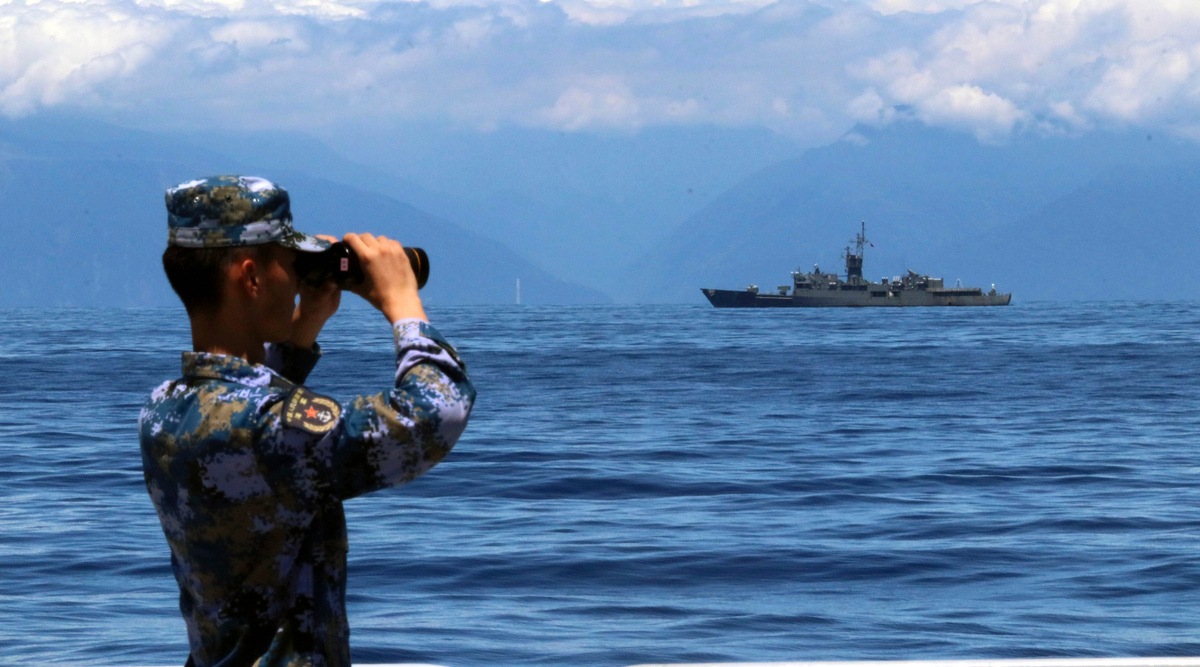 In this photo provided by China's Xinhua News Agency, a People's Liberation Army member looks through binoculars during military exercises as Taiwan's frigate Lan Yang is seen at the rear on Aug. 5, 2022. (AP)