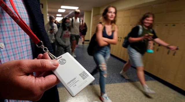 Brent Kiger, Olathe Public Schools' director of safety service, displays a panic-alert button while students at Olathe South High School rush between classes. (AP)