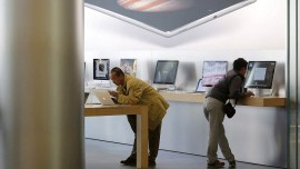 Men try apple's MacBook laptops at an apple store in Beijing