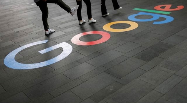 Employees pose for photos with a Google logo outside their office, in Singapore