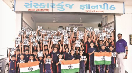 Paresh Patel, trustee of Sansakarkunj Gyanpeeth, with students after distributing flags. (Express Photo)