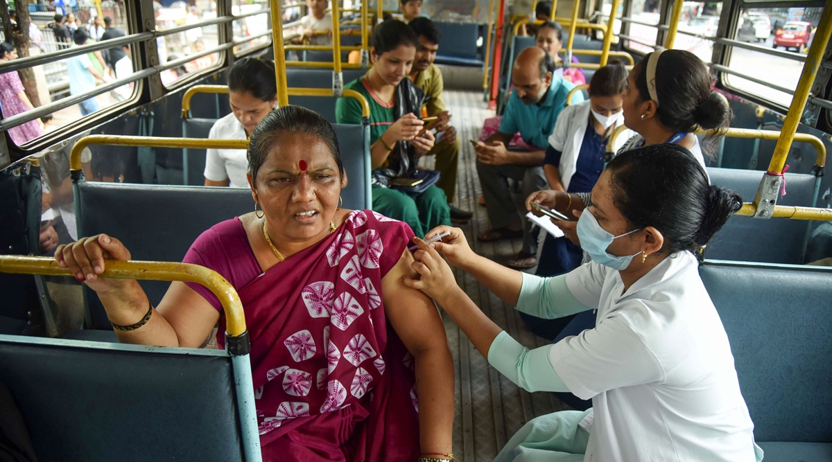 A Navi Mumbai Municipal Corporation (NMMC) worker administers precautionary booster dose of Covid-19 vaccine to a beneficiary, inside a bus in Navi Mumbai. (PTI)