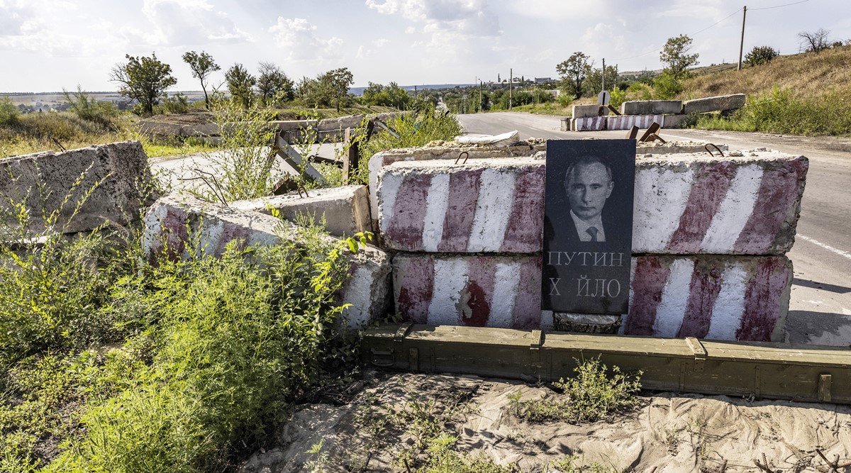 A gravestone with the carved image of Russian President Vladimir Putin leans against a highway checkpoint near Druzhkivka, Ukraine, Aug. 7, 2022. (David Guttenfelder/The New York Times)