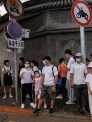 FILE PHOTO: People wear face masks as they stand in a street following a coronavirus disease (COVID-19) outbreak, in Beijing
