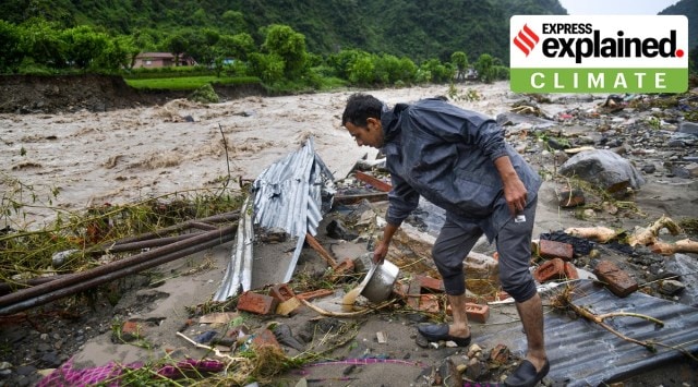 A man salvages his belongings near a swollen river after a series of cloudbursts hit parts of Uttarakhand on Saturday. (PTI Photo)