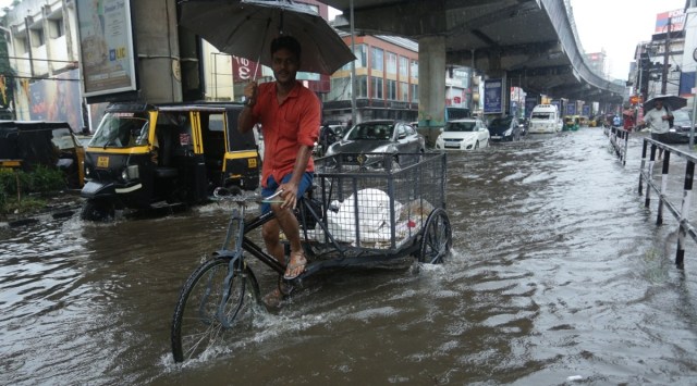 Man cycles through a waterlogged road amid heavy rainfall in Kerala. (Express Photo by Sanjay Mohan)