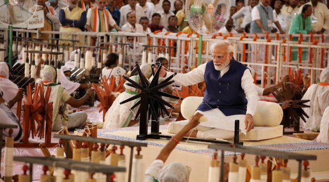 PM Narendra Modi spins a charkha along with 7,500 weavers in Ahmedabad on Saturday. (Express Photo by Nirmal Harindran)