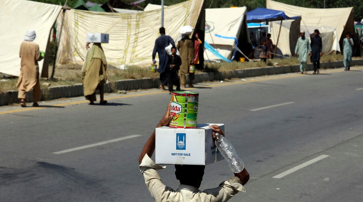 Displaced families receive food and take refuge on a roadside after fleeing their flood-hit homes, in Charsadda, Pakistan (AP Photo/Mohammad Sajjad)
