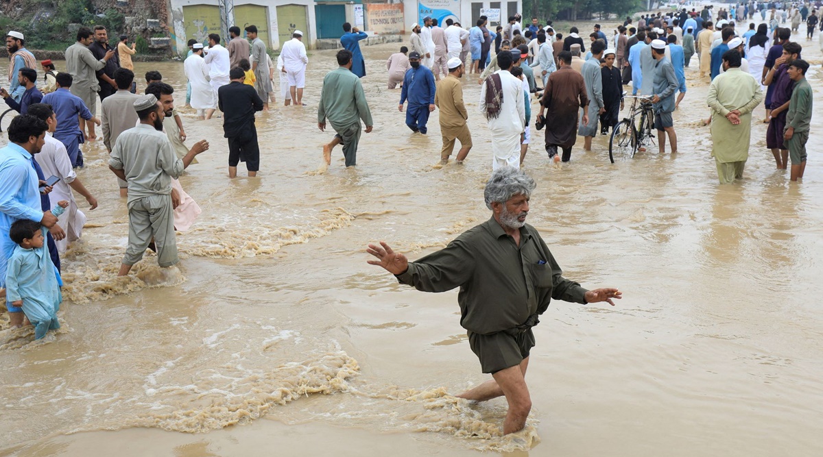 A man balances himself as he, along with others, walks on a flooded road, following rains and floods during the monsoon season in Charsadda, Pakistan. (REUTERS/Fayaz Aziz)