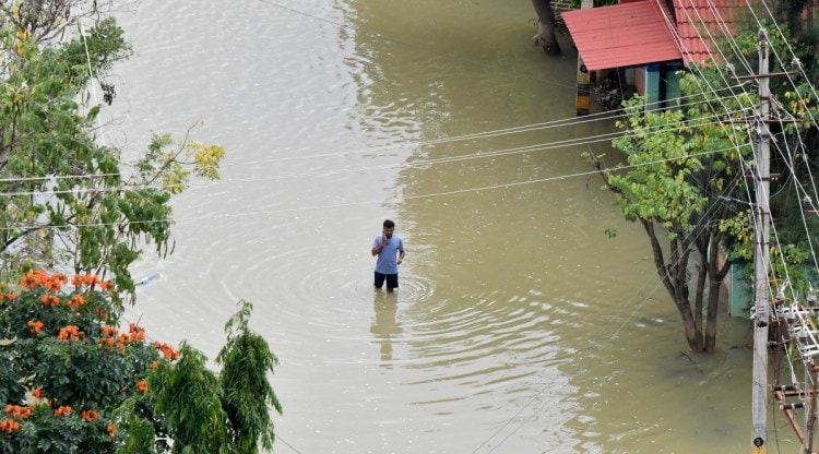 A man speaks on his mobile phone as he wades through a water-logged road in a residential area following torrential rains in Bengaluru, India, September 7, 2022. REUTERS/Samuel Rajkumar