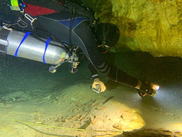 Octavio del Rio films a pre-historic human skeleton partly covered by sediment in an underwater cave