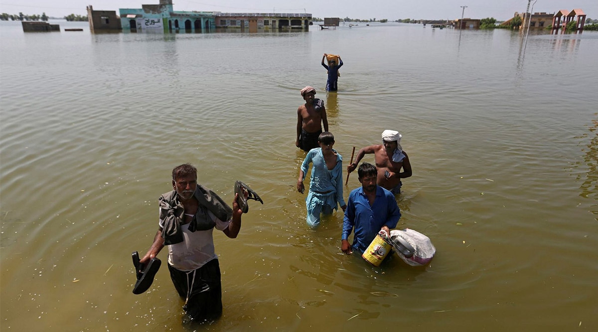 Victims of flooding from monsoon rains carry belongings salvaged from their flooded home in the Dadu district of Sindh Province, of Pakistan