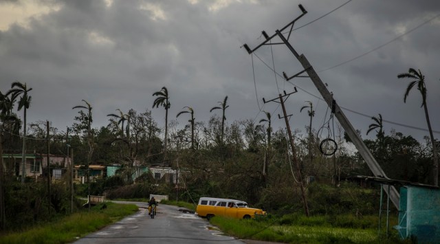 A classic American car drives past utility poles tilted by Hurricane Ian in Pinar del Rio, Cuba, Tuesday, Sept. 27, 2022. (AP Photo)