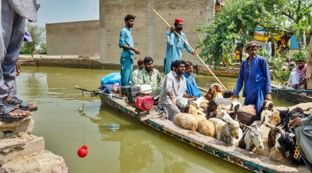 Local residents and their belongings are transported by boat through a flooded area of Johi, Pakistan, on Sept 13, 2022. (Kiana Hayeri/The New York Times)