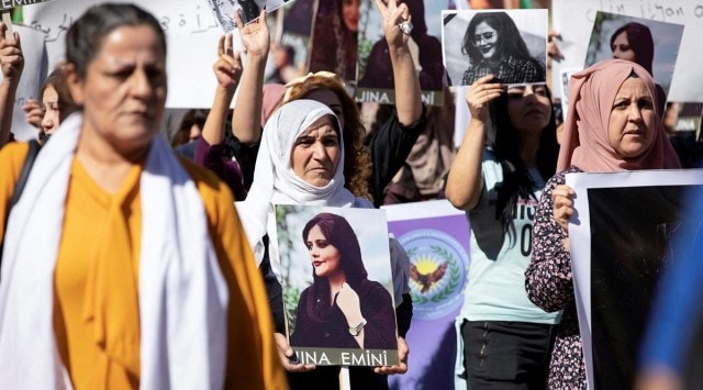 Women carry pictures during a protest over the death of 22-year-old Kurdish woman Mahsa Amini in Iran, in the Kurdish-controlled city of Qamishli, northeastern Syria, September 26, 2022. (REUTERS)