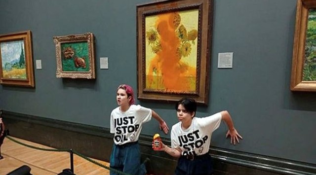 Activists of "Just Stop Oil" glue their hands to the wall after throwing soup at a van Gogh's painting "Sunflowers" at the National Gallery in London, Britain October 14, 2022. (Just Stop Oil/Handout via REUTERS)