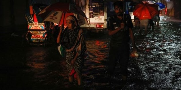 A woman wades through water as streets are flooded due to continuous rain, before the Cyclone Sitrang hits in Dhaka