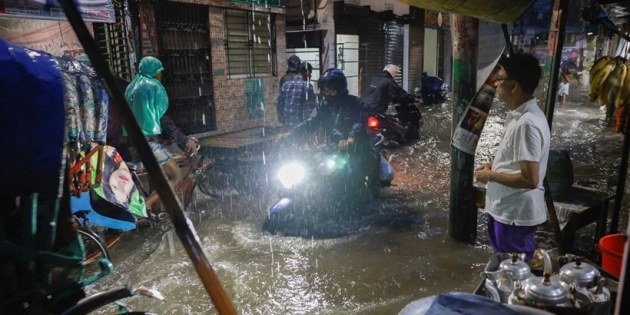 People ride rickshaws and motorcycle on a flooded street, amid continuous rain before the Cyclone Sitrang hits in Dhaka