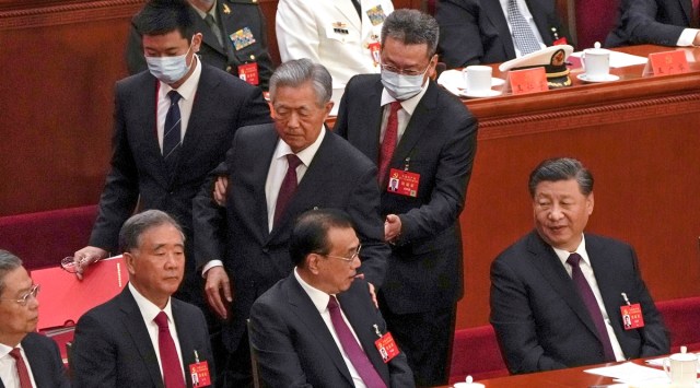 Chinese President Xi Jinping, right, looks on as former Chinese President Hu Jintao, standing at center, touches the shoulder of Premier Li Keqiang, center, as he is assisted to leave the hall during the closing ceremony of the 20th National Congress of China's ruling Communist Party at the Great Hall of the People in Beijing, Oct. 22, 2022. (AP)