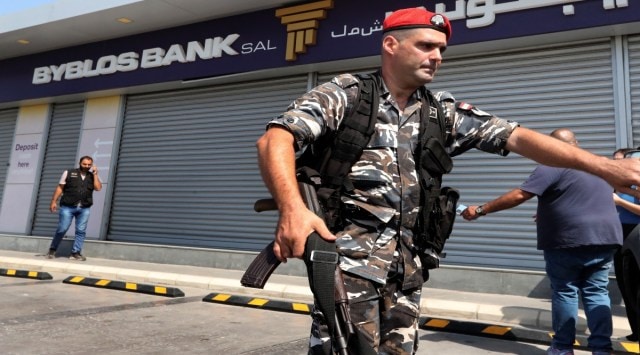 Lebanese security officers stand outside a Byblos Bank branch that was broken into by depositor Ali Hodroj holding a handgun, firing a warning shot and demanding about $40,000 of his trapped savings, in Tyre, south Lebanon, Tuesday, Oct. 4, 2022.  (AP Photo/Mohammed Zaatari)