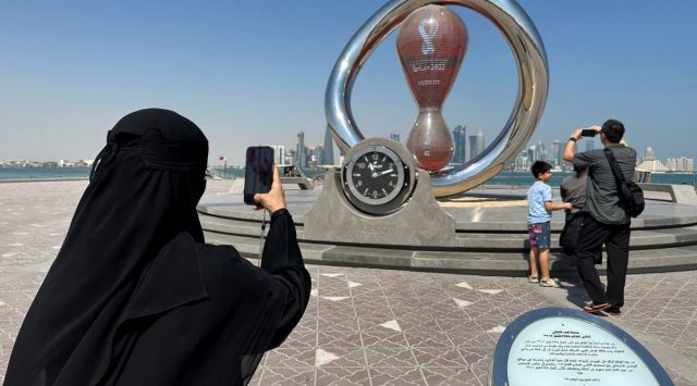 A woman takes a photograph of the FIFA World Cup Qatar 2022 countdown clock . (Reuters)