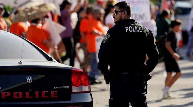 A Uvalde police officer watches as family and friends of those killed and injured in the school shootings at Robb Elementary take part in a protest march and rally, Sunday, July 10, 2022, in Uvalde, Texas. (AP)