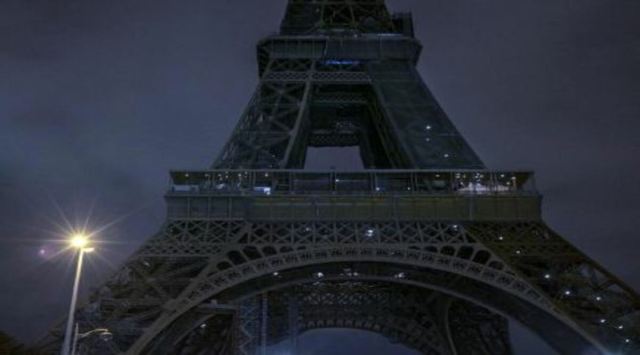 A dimmer Eiffel Tower shortly before midnight on Sept. 23, 2022. Paris authorities recently started switching off ornamental lights on monuments earlier than usual as part of a plan to cut energy use by 10 percent this winter. (Mauricio Lima/The New York Times)
