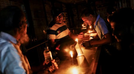 A pharmaceutical shop uses candle lights to serve customers during countrywide blackout in Dhaka, Bangladesh. (REUTERS/Mohammad Ponir Hossain)