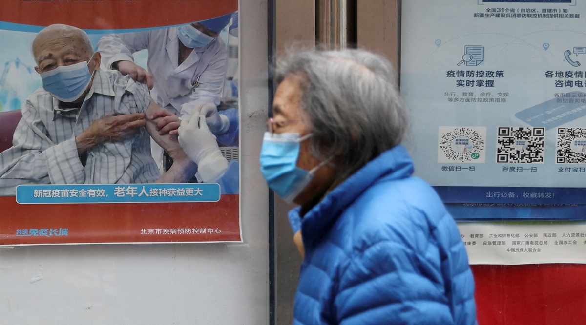 A person walks past a poster encouraging elderly people to get vaccinated against Covid-19, near a residential compound in Beijing, China, March 30, 2022. (Reuters)
