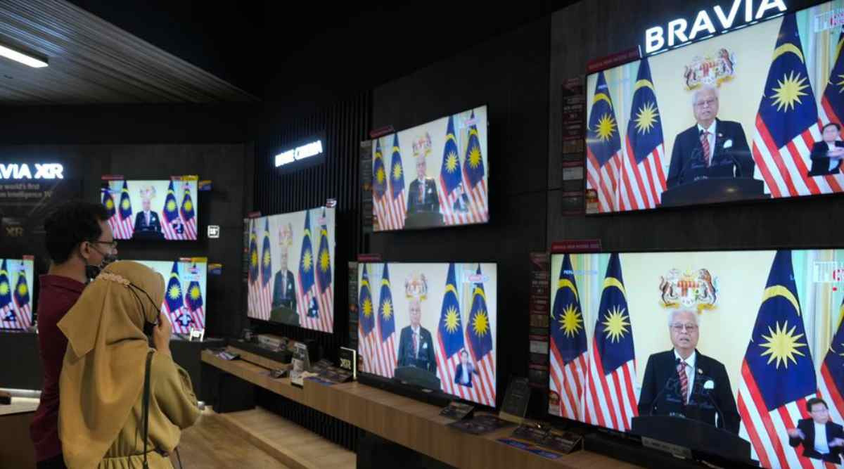 Customers watch a live broadcast of an announcement by Malaysian Prime Minister Ismail Sabri Yaakob at an electronics store in Kuala Lumpur, Monday, Oct. 10, 2022. Ismail announced Monday that Parliament will be dissolved, paving the way for general elections. (AP Photo/Vincent Thian)