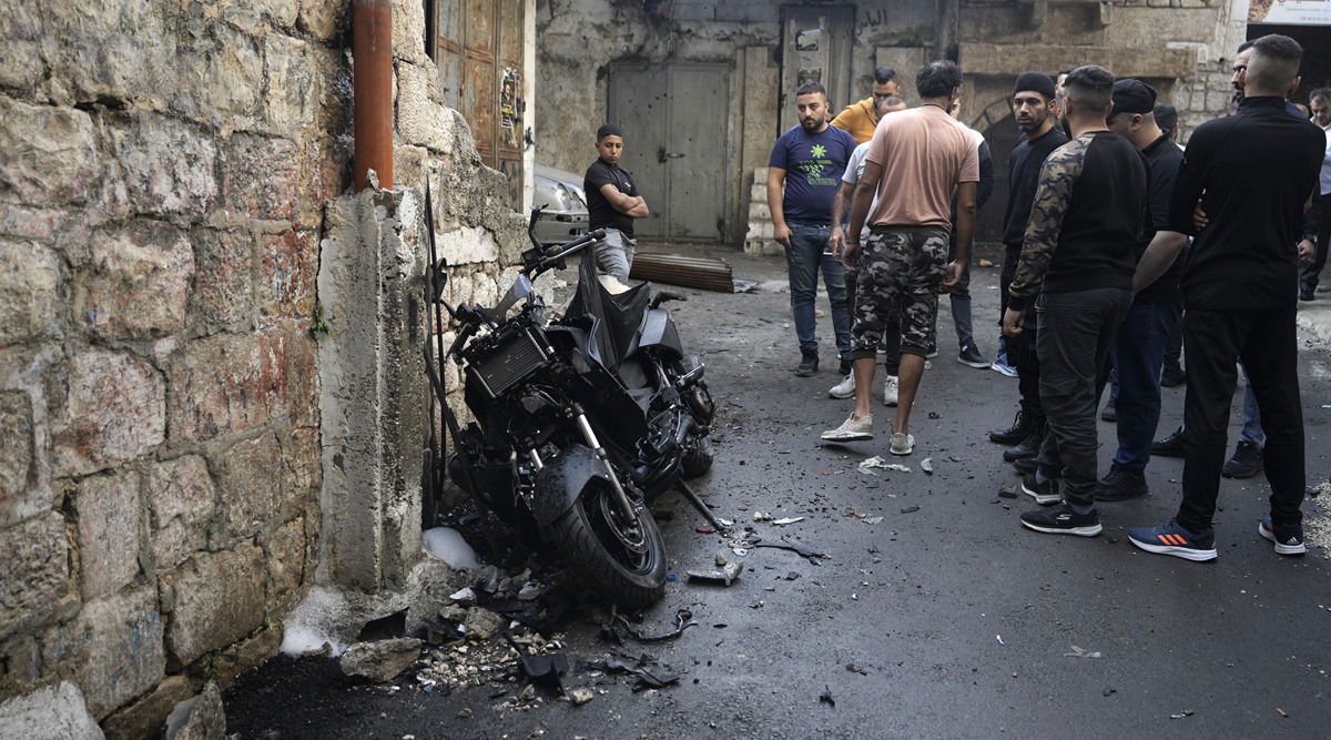 Palestinians gather around the motorcycle that Palestinian militant group Den of Lions says was planted with an explosive device, killing one of its top fighters, Tamer al-Kilani, as he walked past (AP)