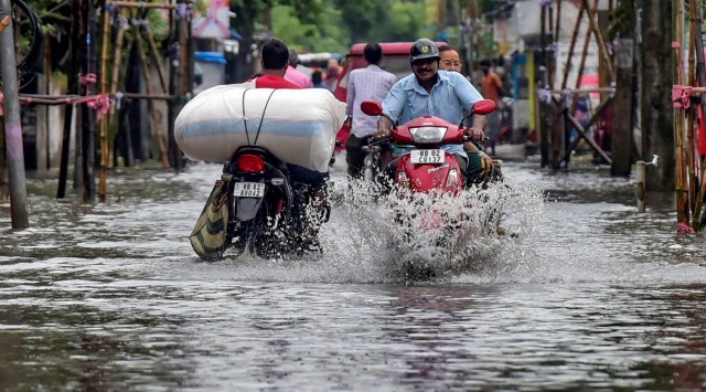 Commuters wade through a waterlogged road after rains, at Balurghat in South Dinajpur district, West Bengal, October 11, 2022. (PTI)
