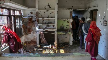 Locals inspect a damaged house, used as a hideout by terrorists, after an encounter between security personnel and militants, at Drach area of Shopian district, Wednesday, Oct. 5, 2022. Four militants were killed in two separate encounters with security forces in J&K's Shopian district. (PTI Photo) 