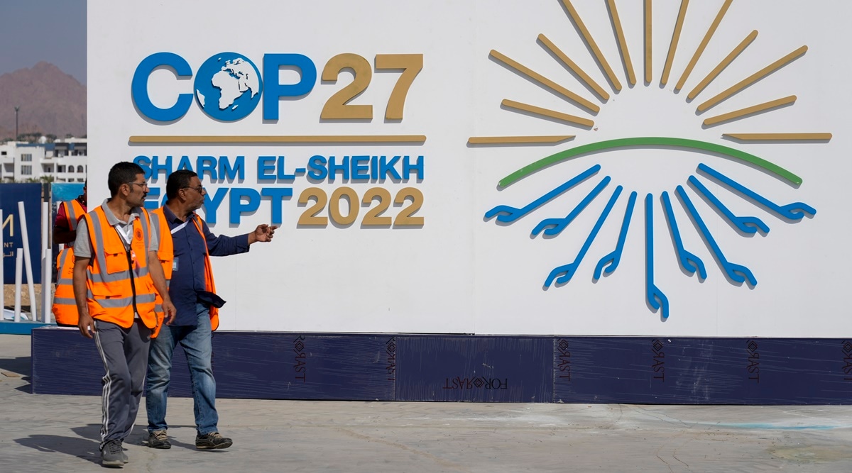 Workers pass a sign at the convention center hosting the COP27 U.N. Climate Summit, Saturday, Nov. 5, 2022, in Sharm el-Sheikh, Egypt. The city will host the COP27 U.N. Climate Summit starting on Nov. 6, and scheduled to end on Nov. 18. (AP Photo)