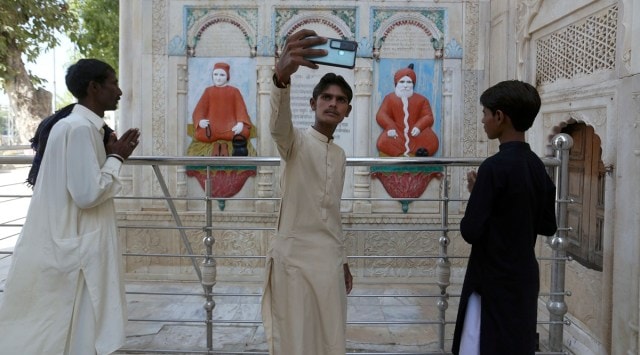 A teenager from Pakistani Hindu community takes selfie with his phone while he with others visit at the Sadhu Bela temple, located in an island on the Indus River, in Sukkur, Pakistan, Wednesday, Oct. 26, 2022. (AP Photo/Fareed Khan)