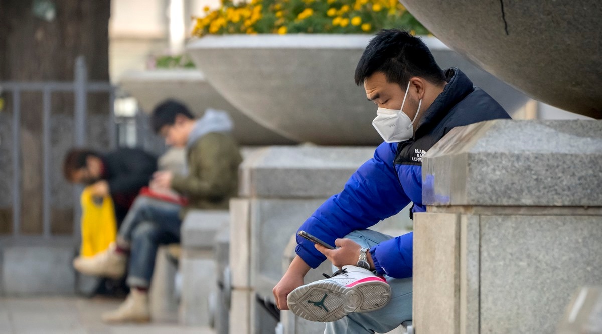 A man wearing a face mask sits on a bench at the Wangfujing shopping district in Beijing, Saturday (AP)