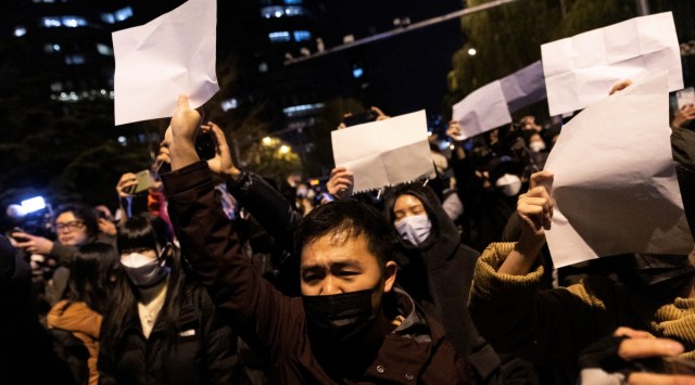 People hold white sheets of paper in protest over coronavirus disease (COVID-19) restrictions, after a vigil for the victims of a fire in Urumqi, as outbreaks of COVID-19 continue, in Beijing, China, November 28, 2022.        REUTERS/Thomas Peter/File Photo