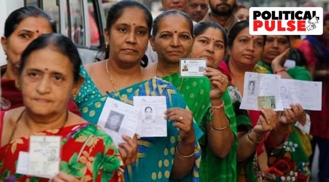 Women display their voter identity cards as they wait to cast their vote during the first phase of the Gujarat state assembly election in Rajkot. (Source: AP Photo)