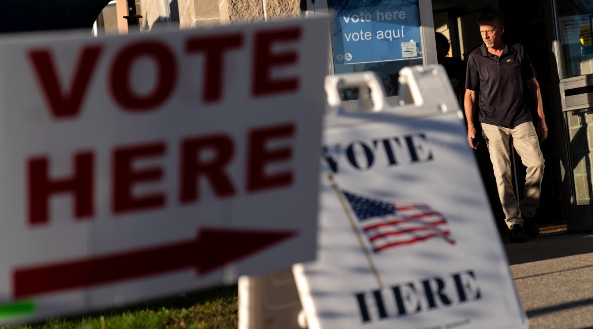 Signs point to the entrance on the last day of early voting before the midterm election as a man walks out of a polling site in Cranston, R.I., Monday, Nov. 7, 2022. (AP Photo/David Goldman)
