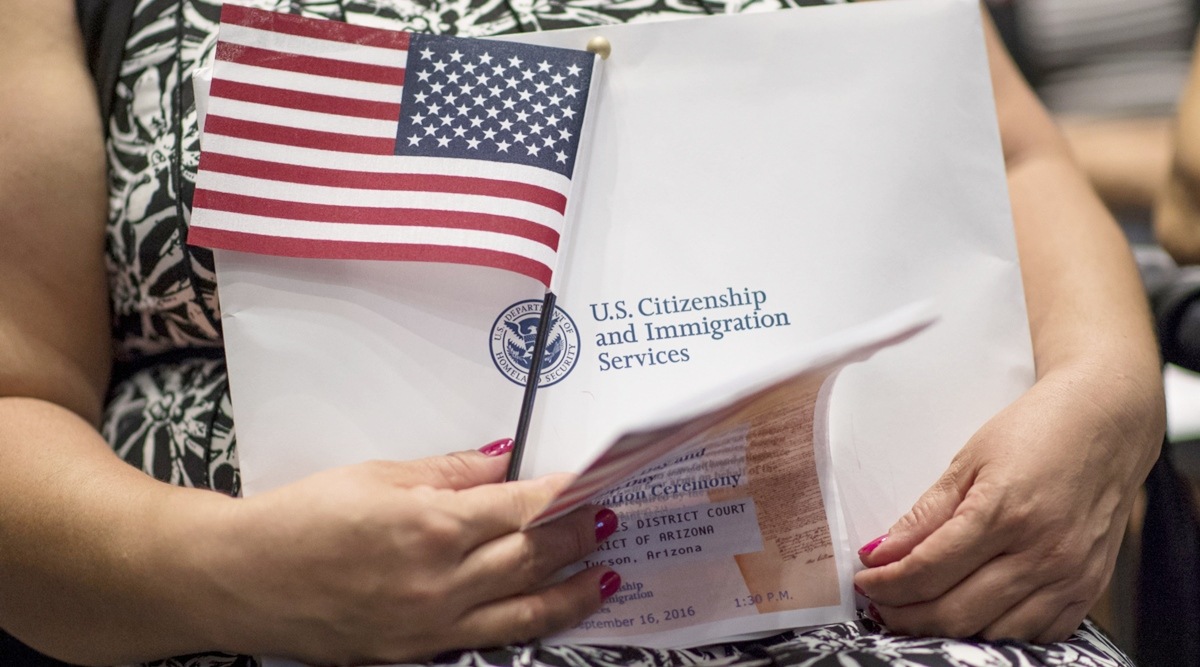 An applicant for US citizenship holds an American flag and paperwork during a naturalisation ceremony at the Evo A DeConcini US Courthouse in Tucson, Arizona, US, on Sept. 16, 2016. (Photographer: David Paul Morris/Bloomberg)