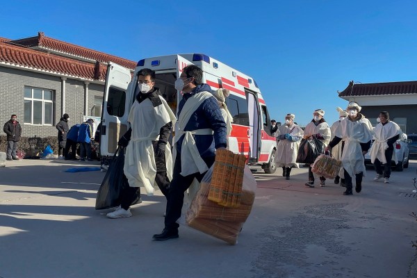 Family members carry bags of paper offering for their deceased relative at Gaobeidian Funeral Home in northern China's Hebei province.