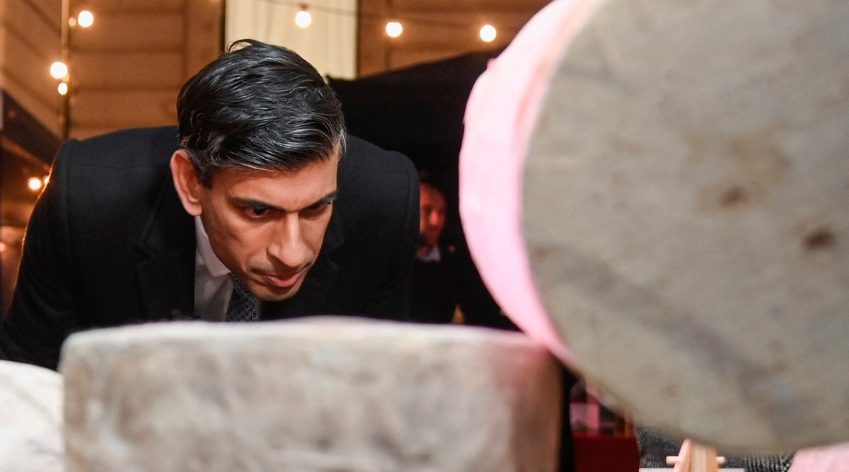 Britain's Prime Minister Rishi Sunak looks at cheeses as he visits a food and drinks market promoting British small businesses at Downing Street in London, Wednesday Nov. 30, 2022. (Toby Melville/Pool via AP)