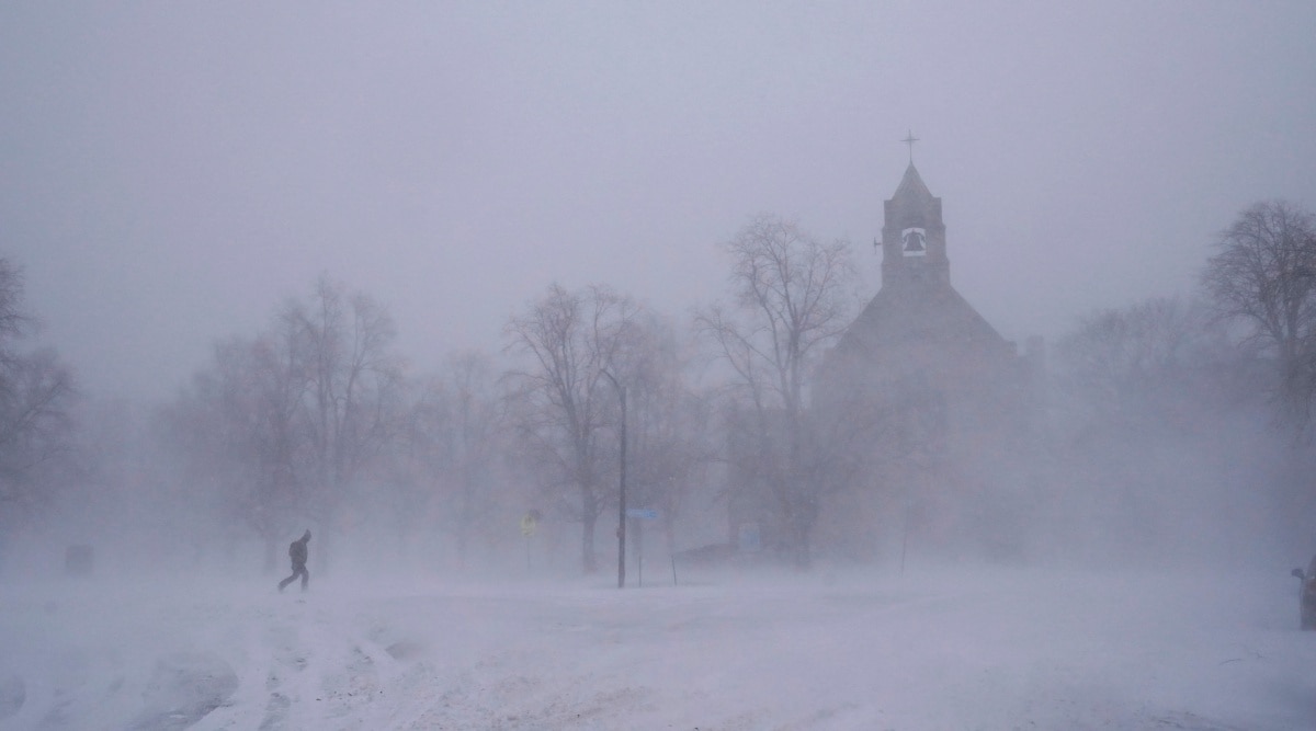 A lone pedestrian in snow shoes makes his way across Colonial Circle as St. John's Grace Episcopal Church rises above the blowing snow amid blizzard conditions in Buffalo, N.Y. on Saturday, Dec. 24, 2022. (Derek Gee/The Buffalo News via AP)