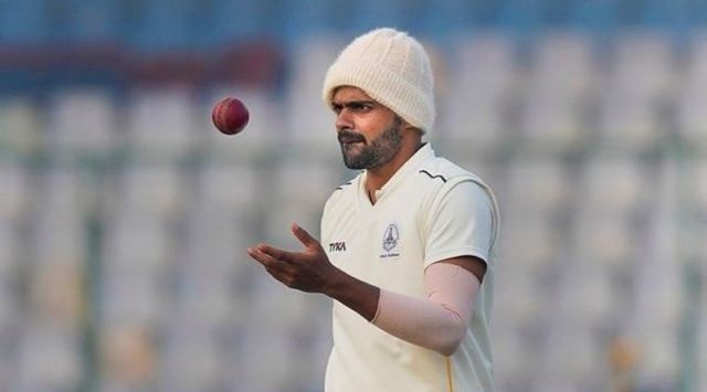 Tamil Nadu bowler Lakshminarayanan Vignesh wears a woollen cap as he bowls on the first day of Ranji Trophy match against Delhi, in New Delhi, Tuesday, Dec. 27, 2022. (PTI Photo)