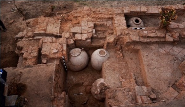Excavation revealing old bricks and earthen pots.