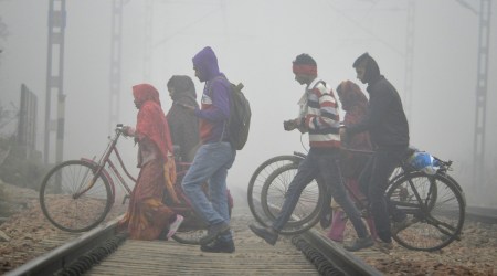 People cross a railway track amid low visibility due to a thick layer of fog, on a cold winter morning, in Gurugram, Monday, Dec. 26, 2022. (PTI Photo)