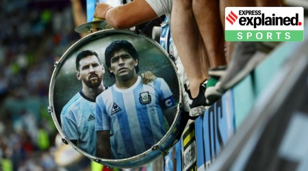 A fan at an Argentina match holds a drum, with its side painted with images of Maradona and Messi.