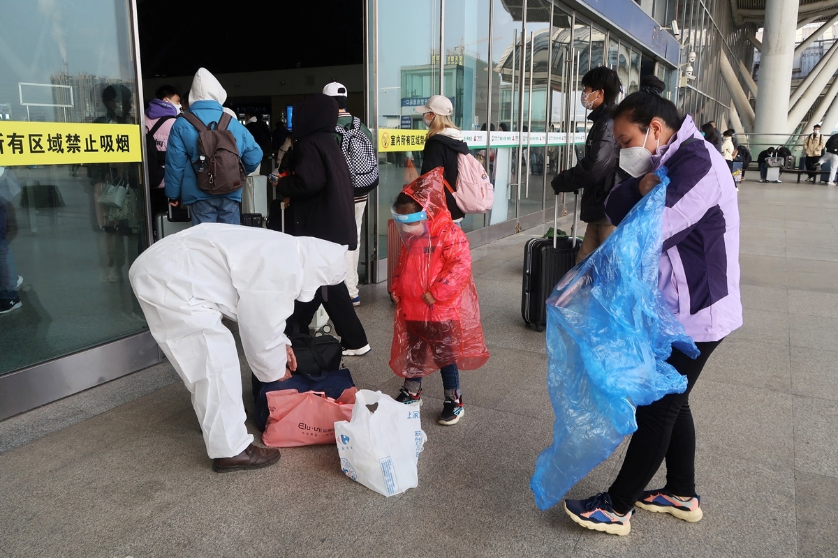 A woman puts on a raincoat as a protective measure at an entrance of a railway station, after the government eased curbs on the coronavirus disease (COVID-19) control, in Wuhan, Hubei province, China December 11, 2022. (REUTERS/Martin Pollard)